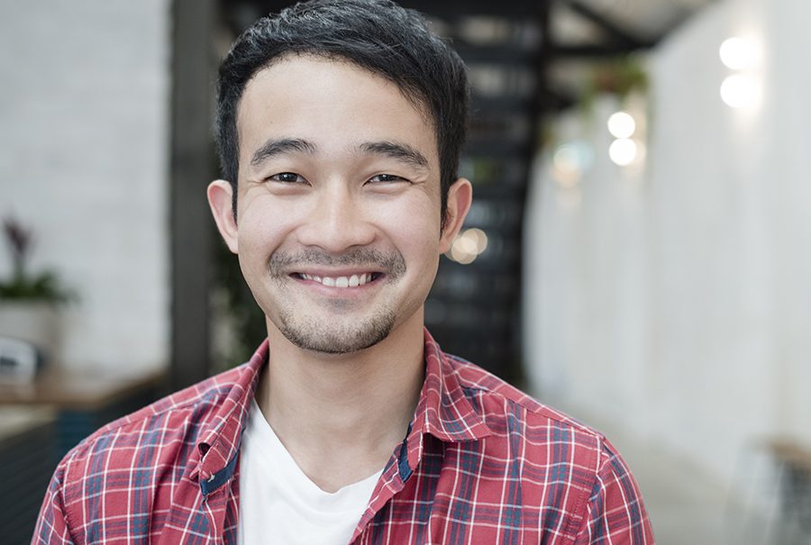 Casual young Asian businessman smiling towards camera